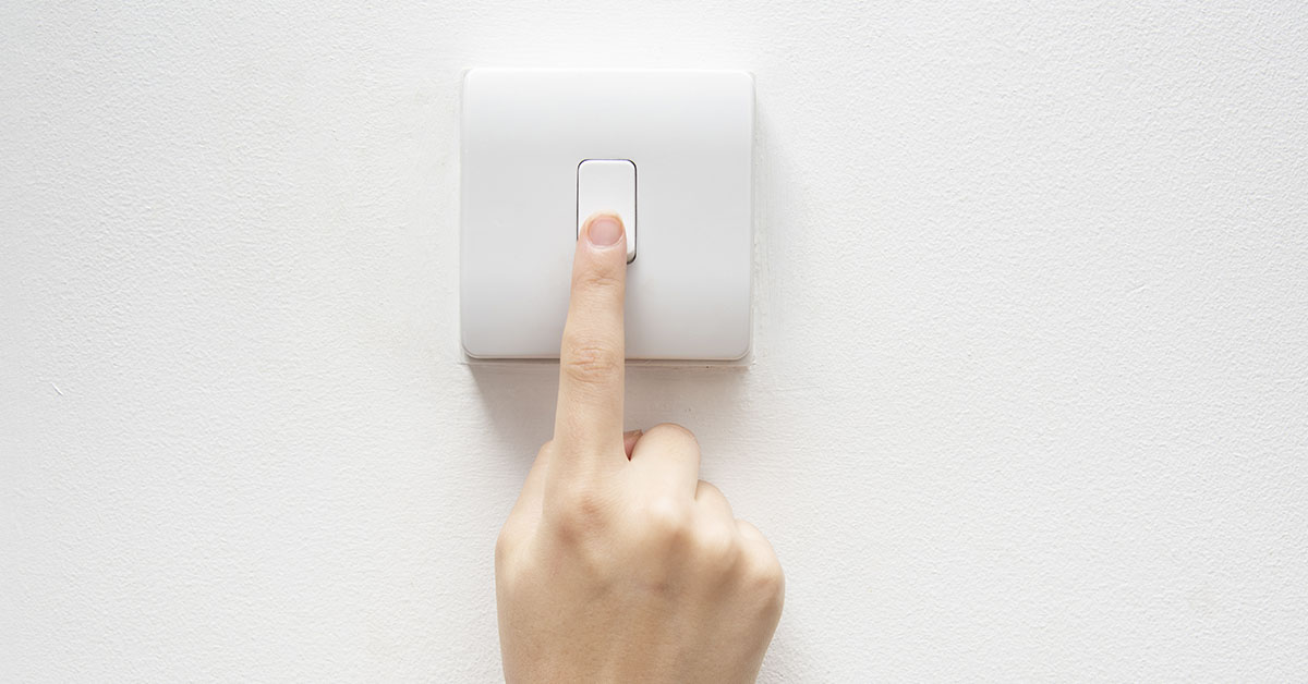 person turning light switch off on wall