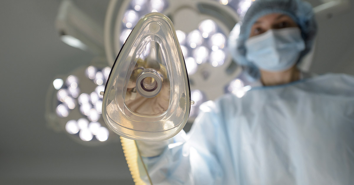Anesthesiologist puts an oxygen mask on the patient. Preparing for surgery. The doctor administers inhalation anesthesia using an anesthesia machine before intubation. Emergency and first aid concept