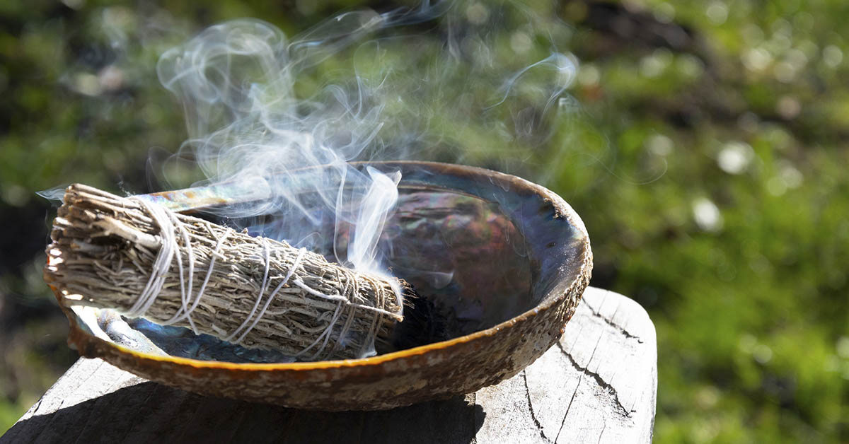 Sage burning in small bowl. Smudging sage benefits concept