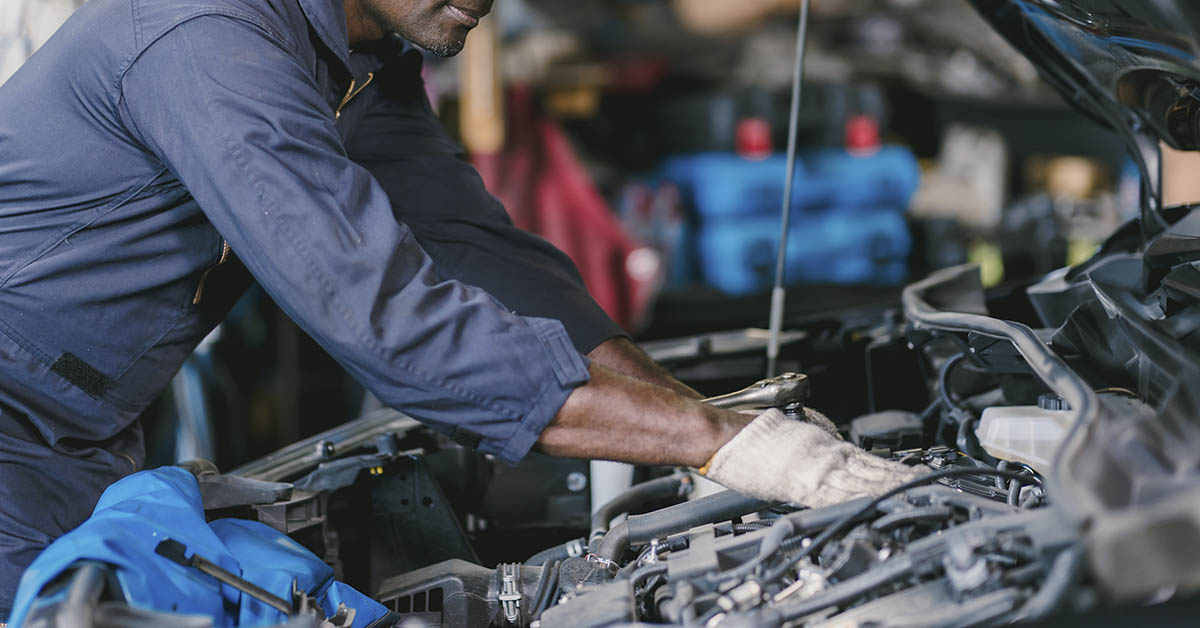 auto mechanic working on engine of a car