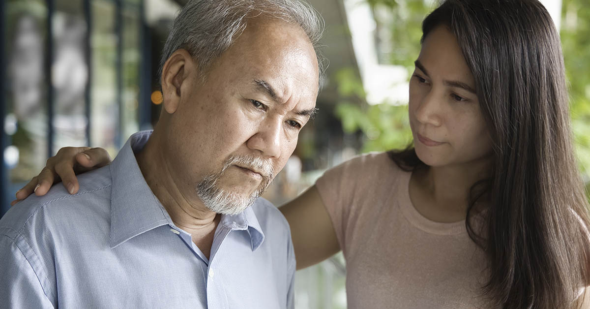 Woman putting hand on the back of an elderly man comforting him