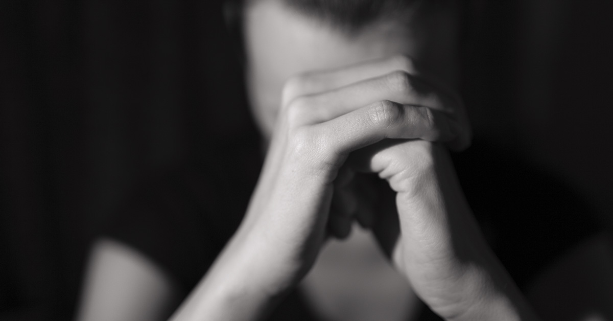 person with their hands clasped together, possibly in prayer or contemplation
