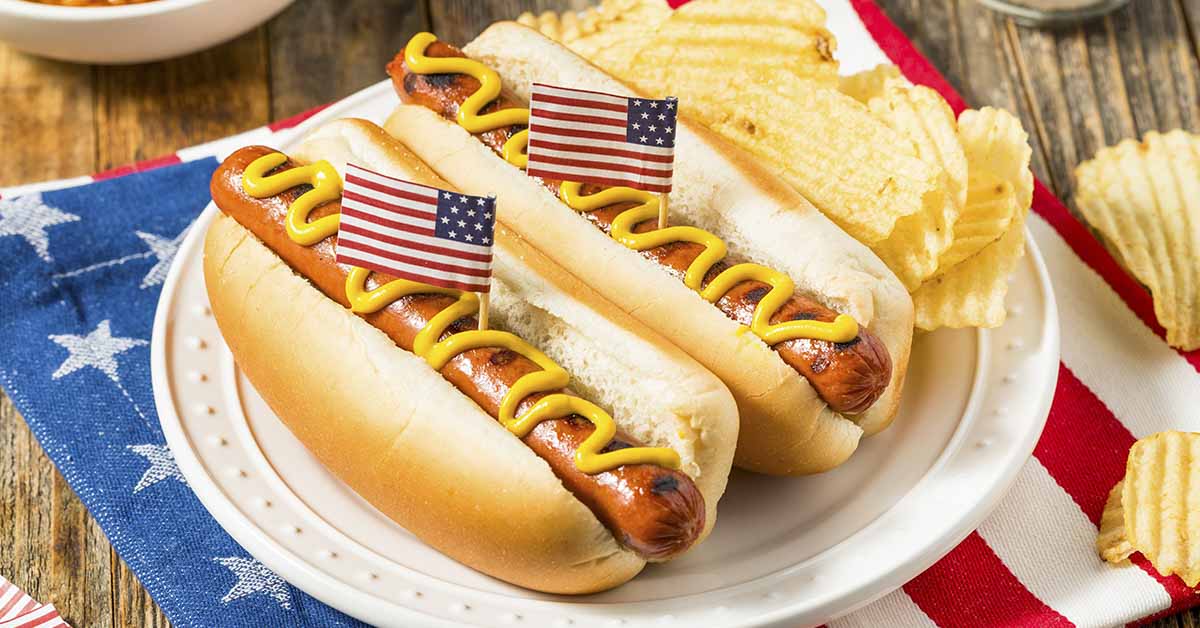 two hot dogs with with small novelty American flags stuck in them