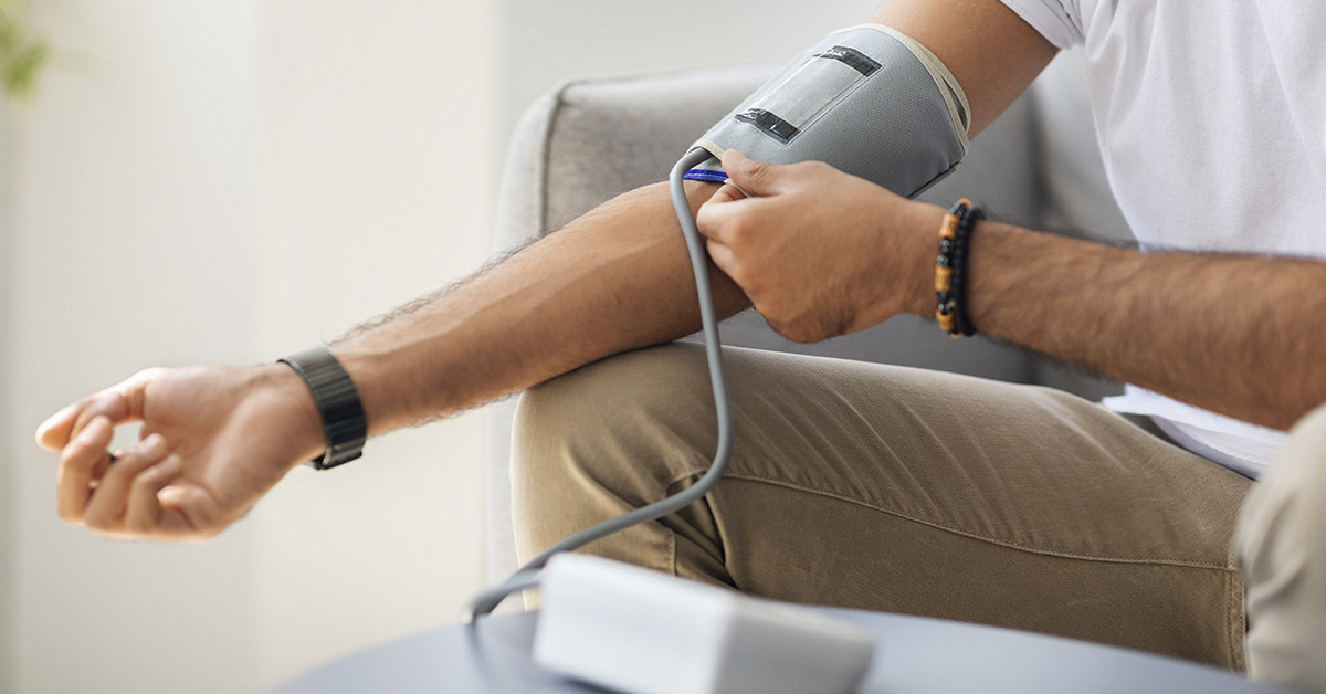 man with blood pressure measuring device (sphygmomanometer) around arm. High blood pressure, vascular, and heart health concept