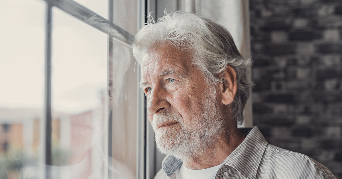 Elderly man looking out a window