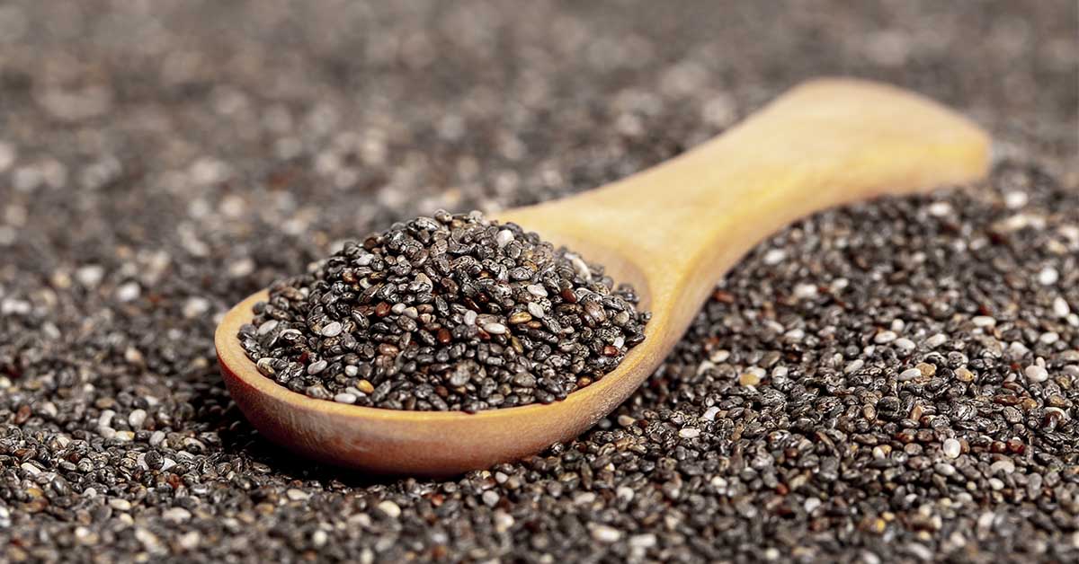Wooden spoon filled with, and in a bed of chia seeds
