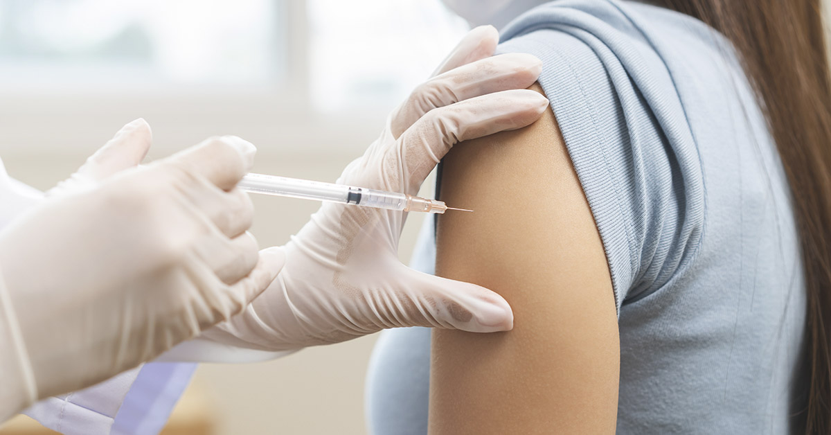 woman getting a vaccine with needle being injected into her shoulder