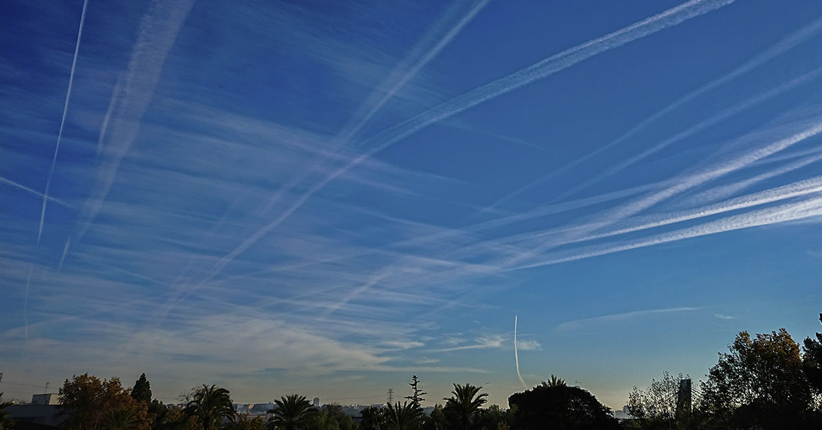Contrails seen in sky as sun sets. Chemtrail conspiracy concept