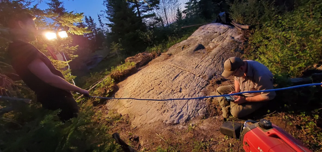 Archeologists working at night with lights illuminating the rune stone in Ontario.