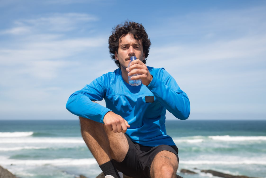 Man in Blue Long Sleeve Shirt Drinking Water in a Plastic Bottle
