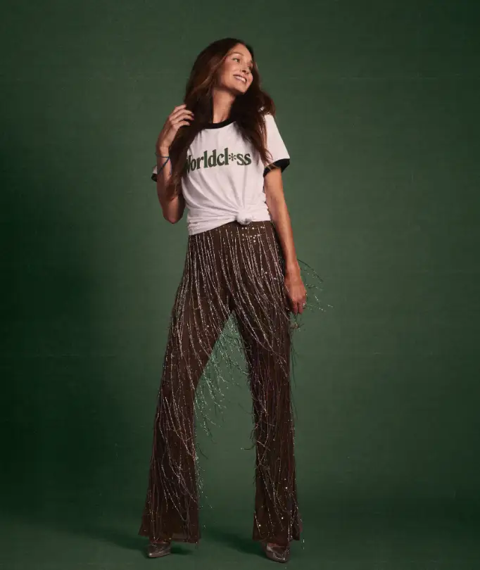 Sarah Beran, colon cancer survivor and Worldclass co-founder, wearing white branded t-shirt and sequined pants in promotional photo.