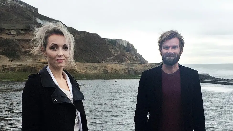 Rape survivor Thordis Elva and Tom Stranger standing together by a coastline.
