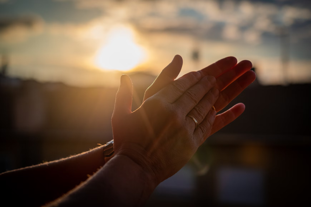 hands clapping with the sun shinning in the background