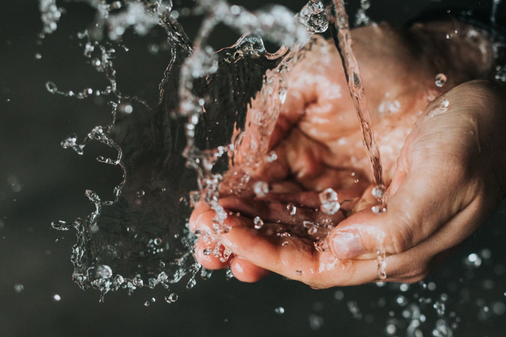 water pouring into hands. Water can be an uncommon cause of hives