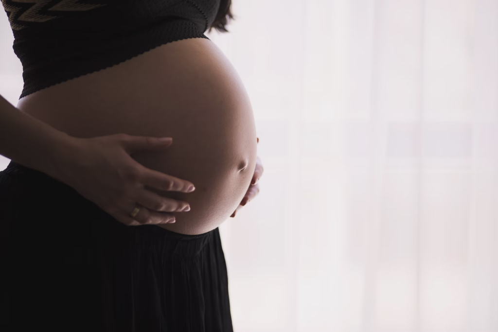 woman's holding pregnant belly. Hormones can be an uncommon cause of hives