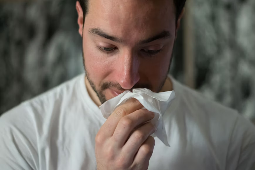 Man wipping his nose with a tissue. Infections are an uncommon cause of hives