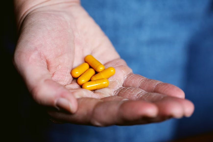 hand holidng yellow capsules