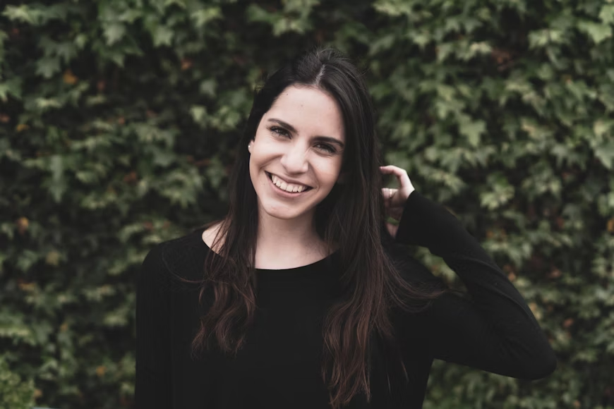 Girl smiling with shrubbery in the background