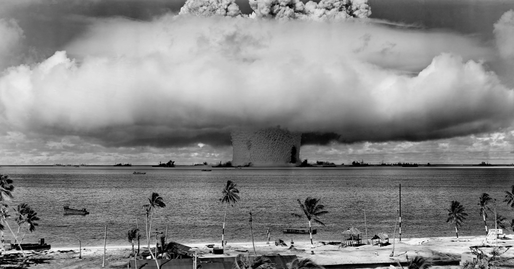 Nuclear weapon test explosion creating massive mushroom cloud over ocean.