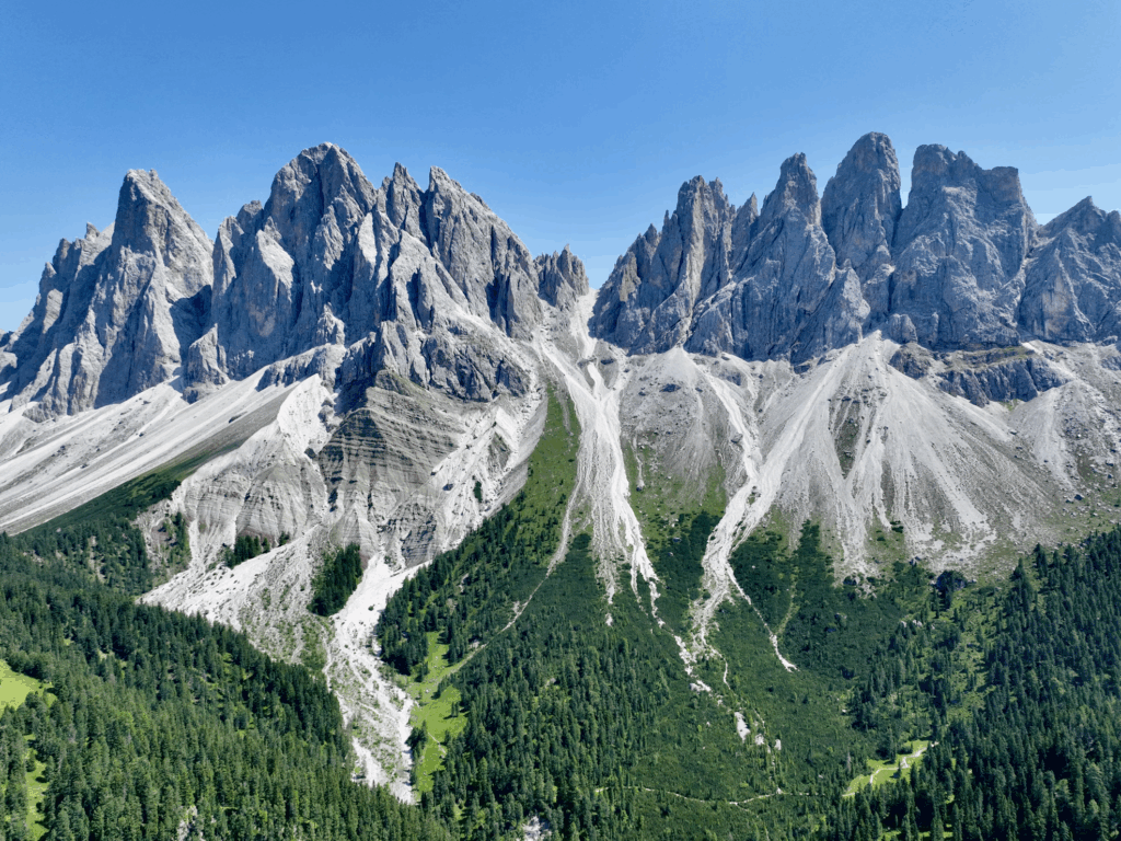 Rocky peaks of the Italian Dolomites rise above green valleys, terrain where melting permafrost can weaken slopes.