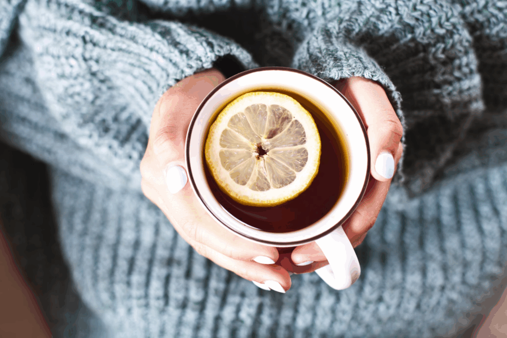 Cozy hands wrapped around a steaming cup with lemon, the perfect health tonic for starting your morning right.