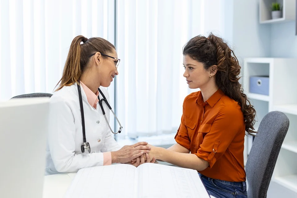 Doctor in white coat with stethoscope consulting with female patient in orange shirt during early signs of cancer evaluation..