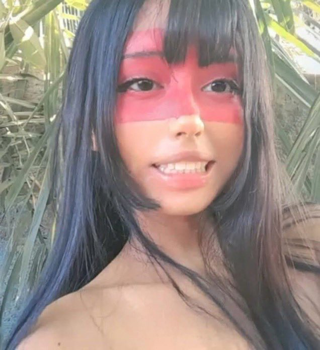 Young woman @SantoriMary in red face paint and minimal clothing cosplaying as Kuruminha, the Brazilian imageboard mascot whose image became the viral Christopher Columbus meme without her consent.