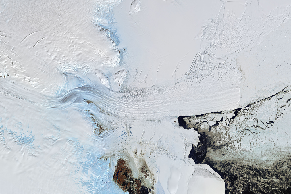 Aerial view of Antarctic ice flows showing the Antarctic discovery where white ice meets exposed dark rock and flowing meltwater channels.