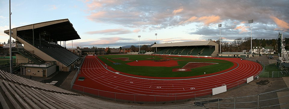 Panoramic view of high school track and field stadium with red running track and grandstand.
