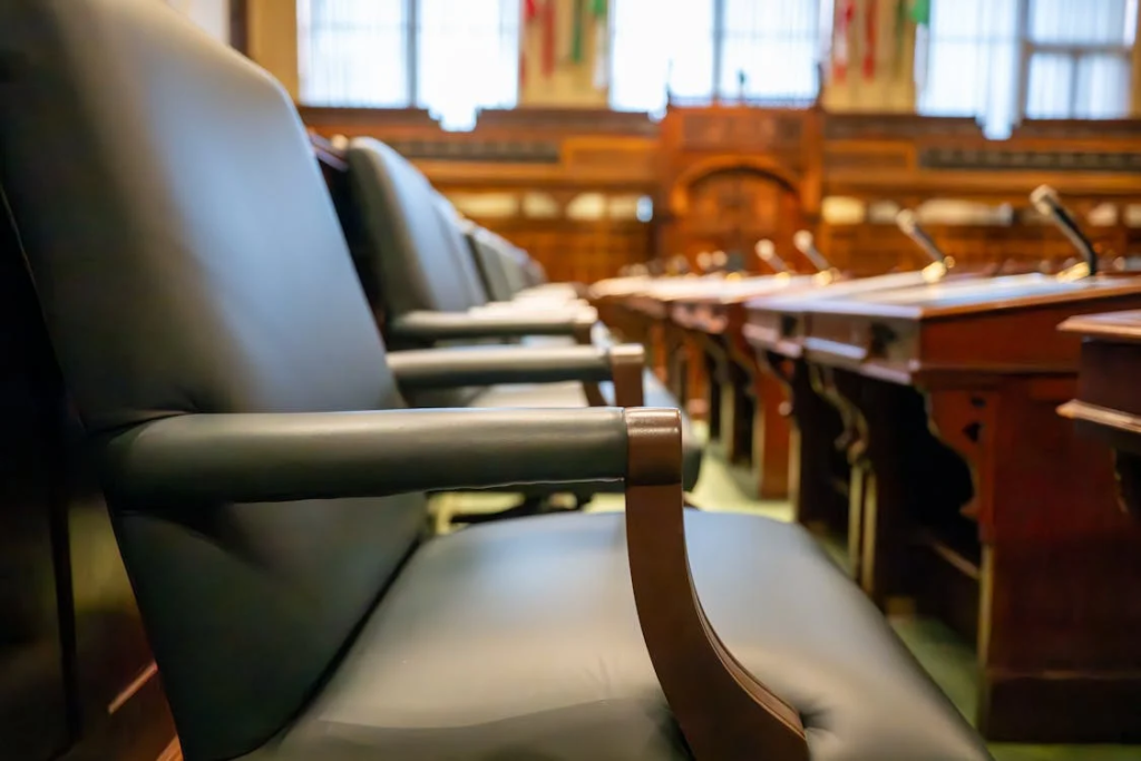 Empty courtroom with wooden benches and judge's chairs, representing judicial proceedings.