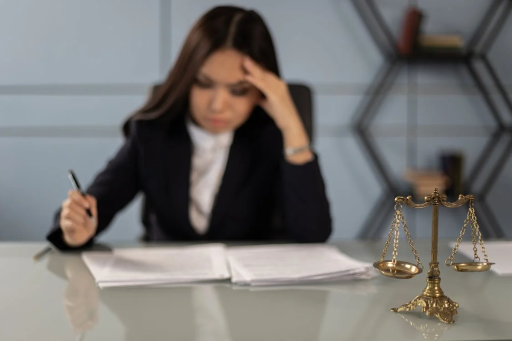 Professional woman reviewing legal documents regarding transgender athlete participation policies with scales of justice on desk.