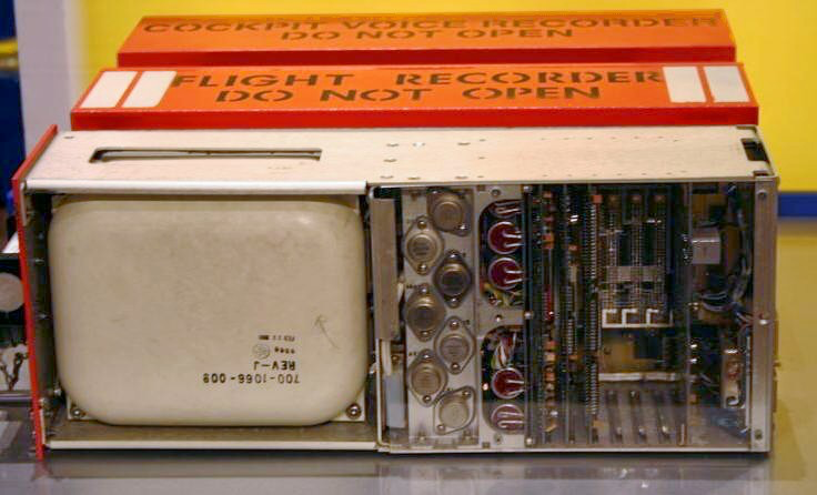 Flight recorder with red warning labels reading 'COCKPIT VOICE RECORDER' and 'DO NOT OPEN', showing internal electronic components.