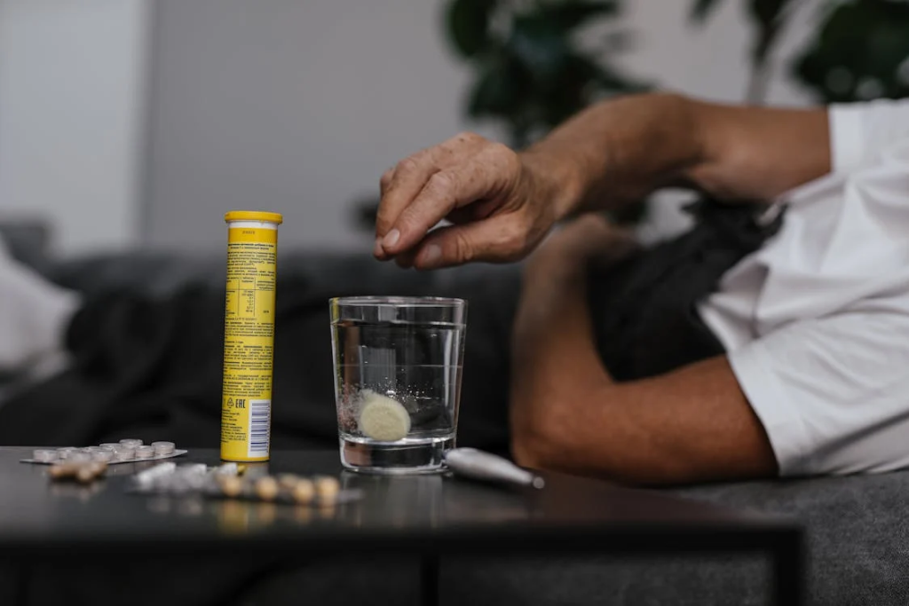 Person Putting Medicine on the Glass of Water