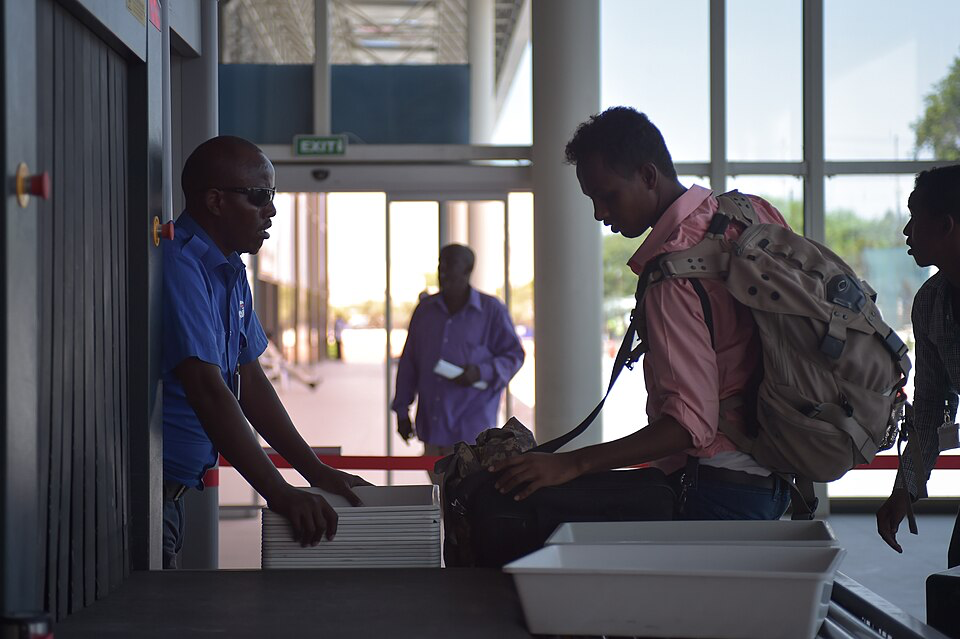 Airport security officer monitoring passenger through screening checkpoint.
