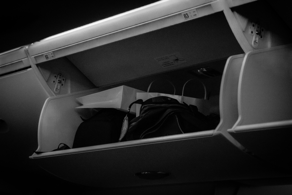 Passenger luggage stored in aircraft overhead compartment.