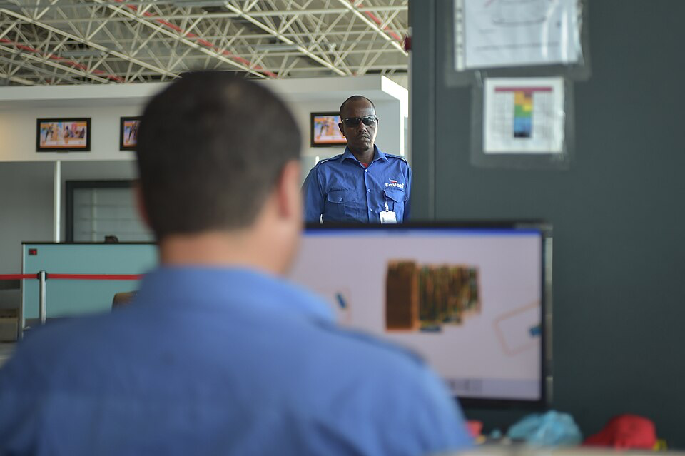 Airport security officer checking passenger luggage.