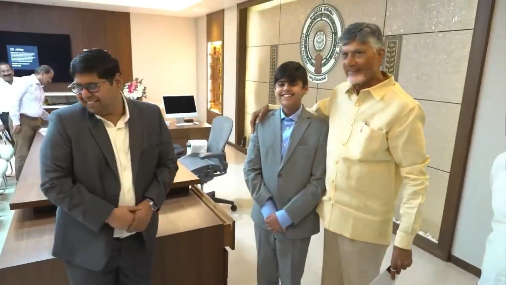 Siddarth Nandyala stands with two officials in a modern office during a meeting about his heart disease detecting technology.