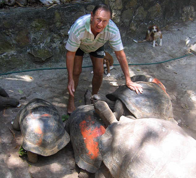 Brendon Grimshaw kneeling beside several giant tortoises on Moyenne Island, part of the wildlife sanctuary he created and protected as a national park.
