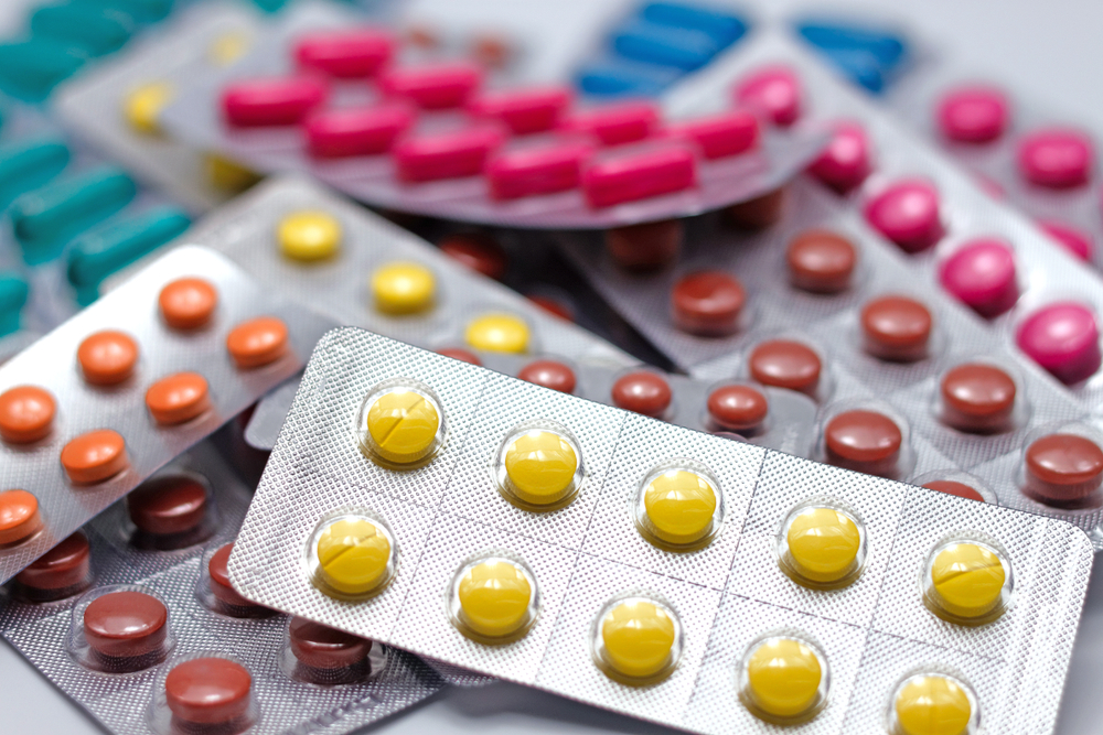 Pile of different medicines NSAIDS group in blister strip packs on white background. Isolated and selective close-up focus.
