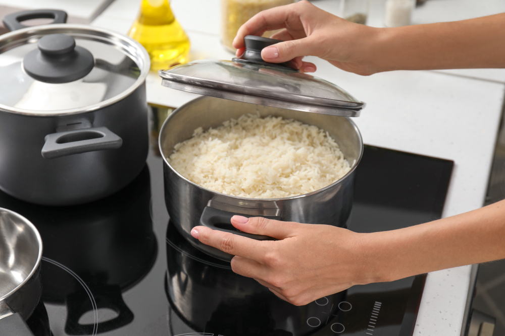 Woman cooking rice on stove in kitchen