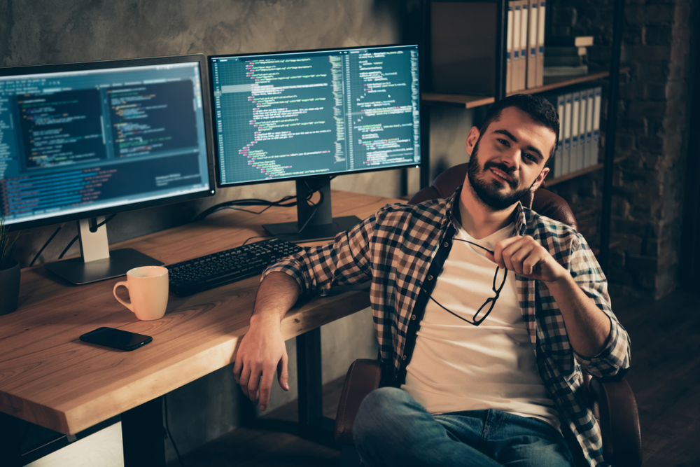 Portrait of his he nice attractive confident content bearded guy wearing checked shirt expert specialist nerd shark boss genius at wooden industrial interior work place station