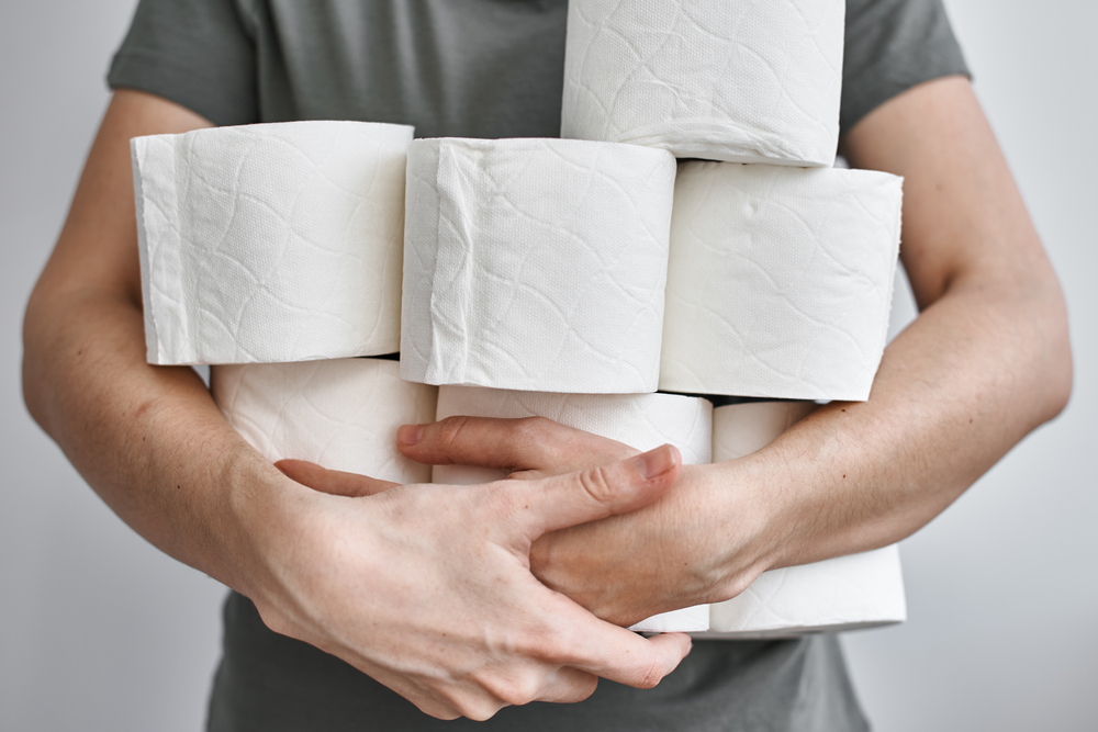 People are stocking up toilet paper for home quarantine from coronavirus. Woman holds many rolls of toilet paper