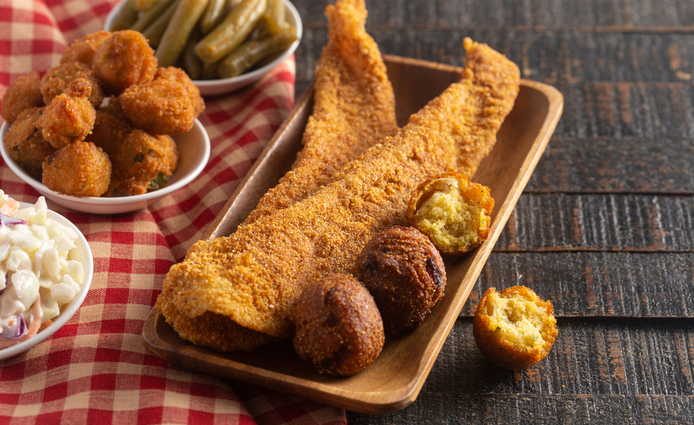 Breaded and Fried Fillets of Fish with Hushpuppies on a Rustic Wooden Table