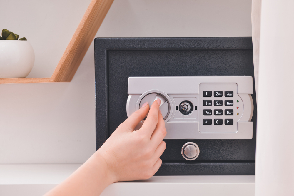 Woman opening modern safe indoors