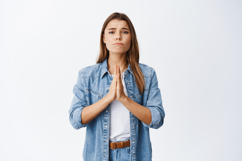 Worried woman need something, begging for help and say please. Girl apologizing, making clingy sad face and pleading you, standing against white background