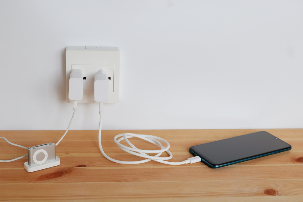 Plug in power outlet Adapter cord charger of smart phone and mp3 players, gadgets, on wooden floor
