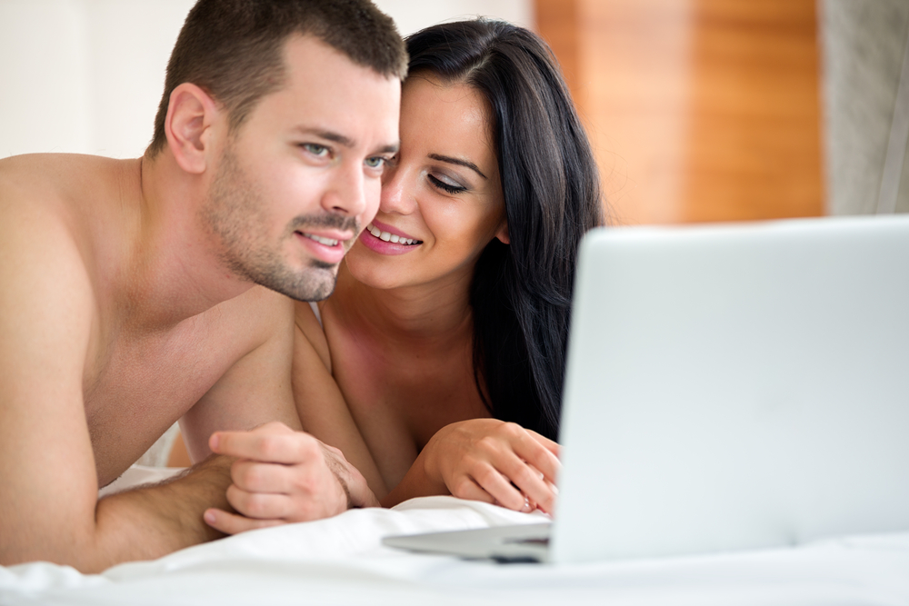 Couple watching porn movie over laptop in bedroom 