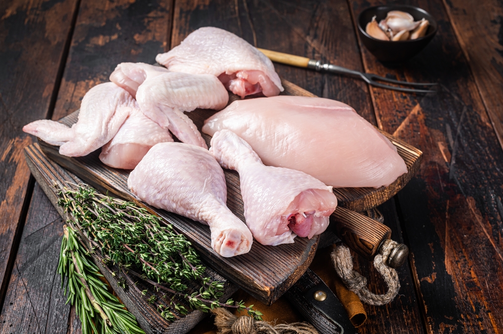 Assortment of chicken portions for Bbq grilling. Raw parts - drumstick, breast fillet, wings, thigh. Wooden background. Top view