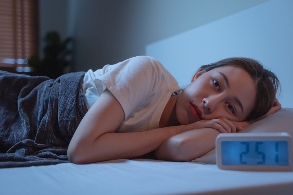 Asian women opened eyes lying on the bed have an insomnia problems.