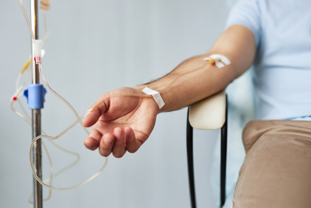 Minimal closeup of male arm with IV drip infusion in treatment session at clinic